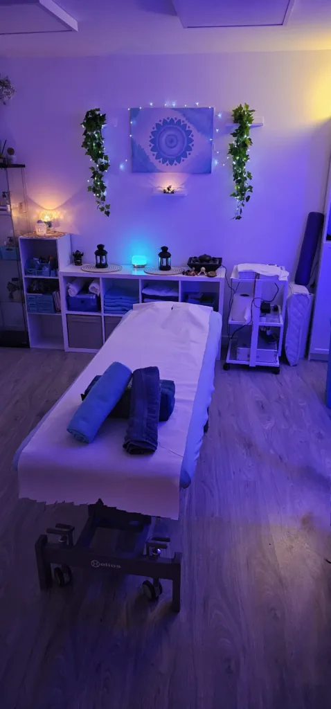 Sala de terapias con la camilla preparada, luz cálida y un mandala en la pared